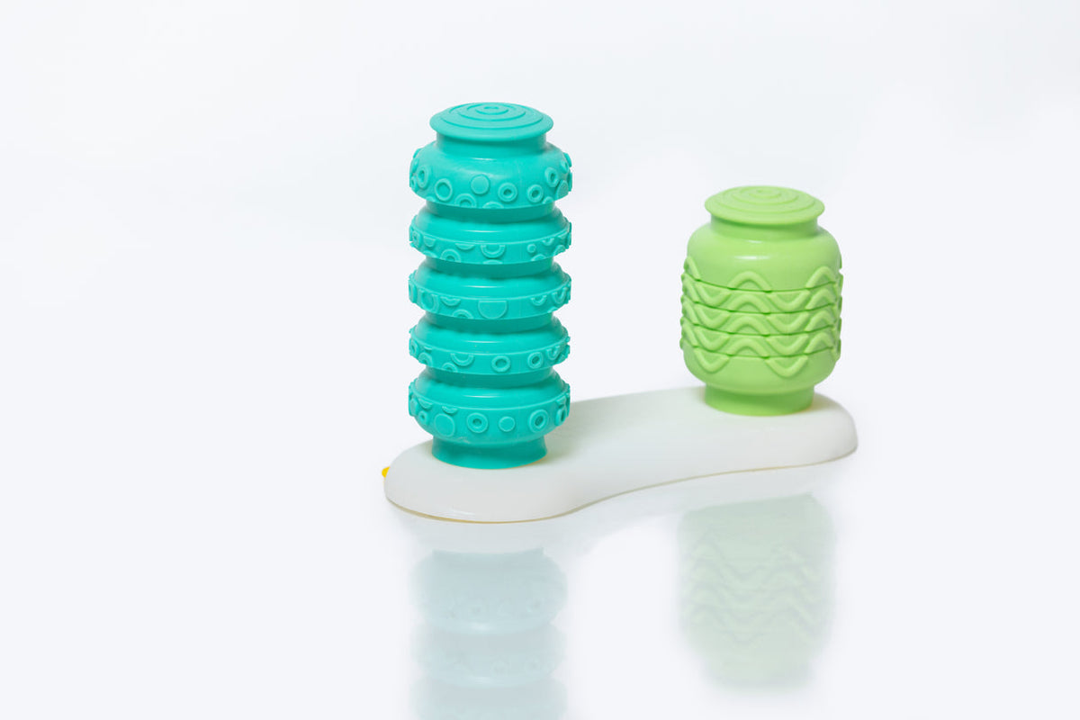 Two textured green and white massage tools on a white background