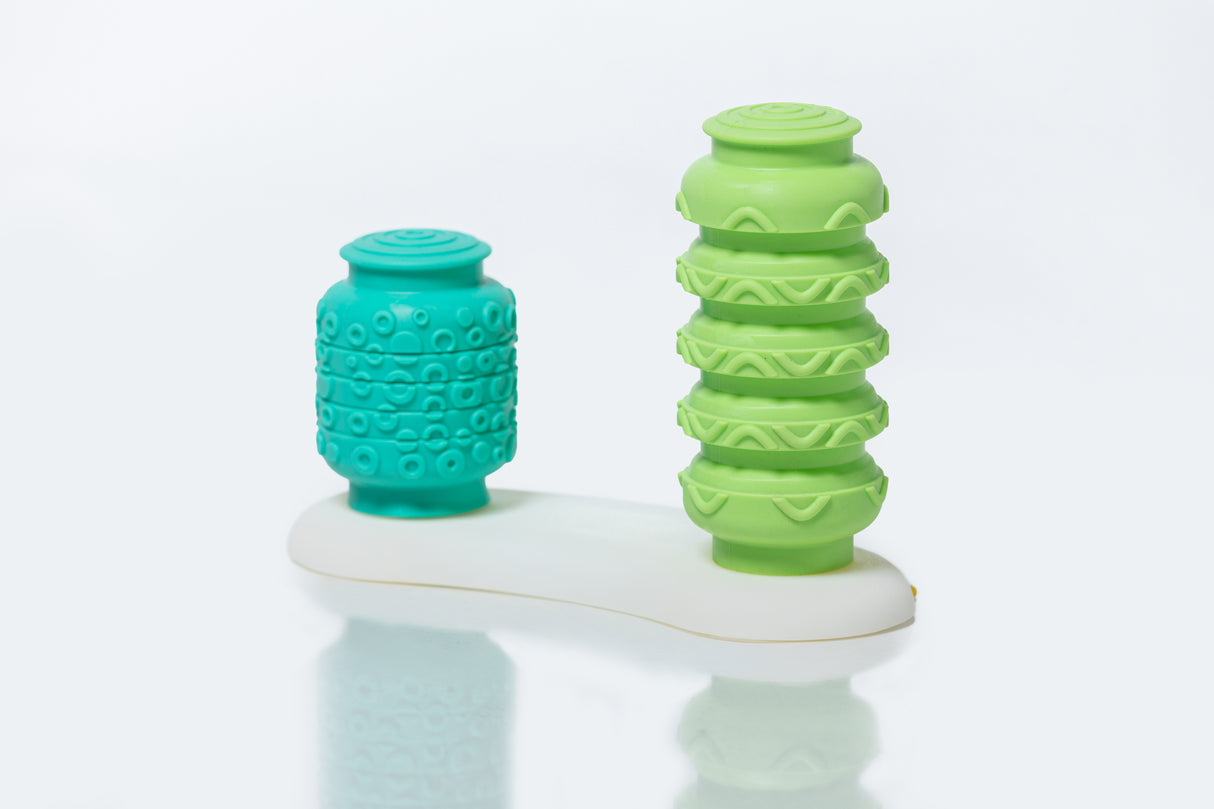 Two massage tools, one teal and one green, on a white surface with a light gray background.
