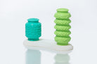 Two massage tools, one teal and one green, on a white surface with a light gray background.