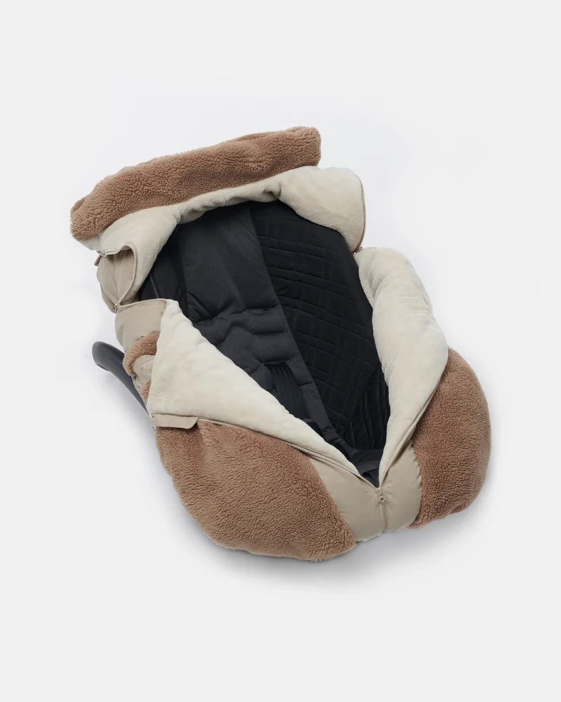 Benji Applique Car Seat Cocoon by 7AM Enfant featuring a dark grey or black weatherproof outer shell, brown sherpa fleece trim around the face opening and zippered side pockets, and a central front zipper.

Concise: Benji Appliq