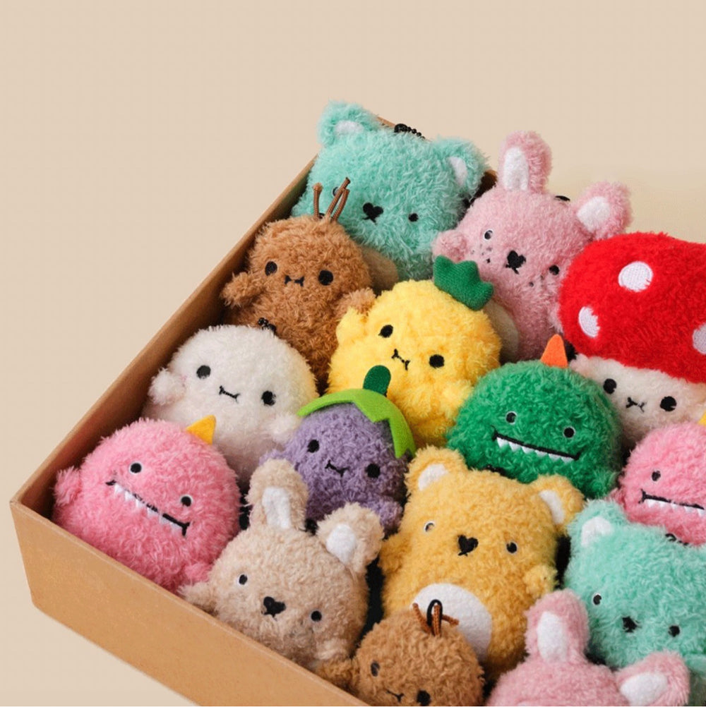 Collection of colorful plush toys in a box on a beige background