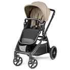 A stroller with a beige canopy and seat liner, a black footmuff, and a dark gray frame, shown from a three-quarter angle on a white background.