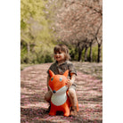 Child holding a fox-shaped toy in a park with cherry blossoms