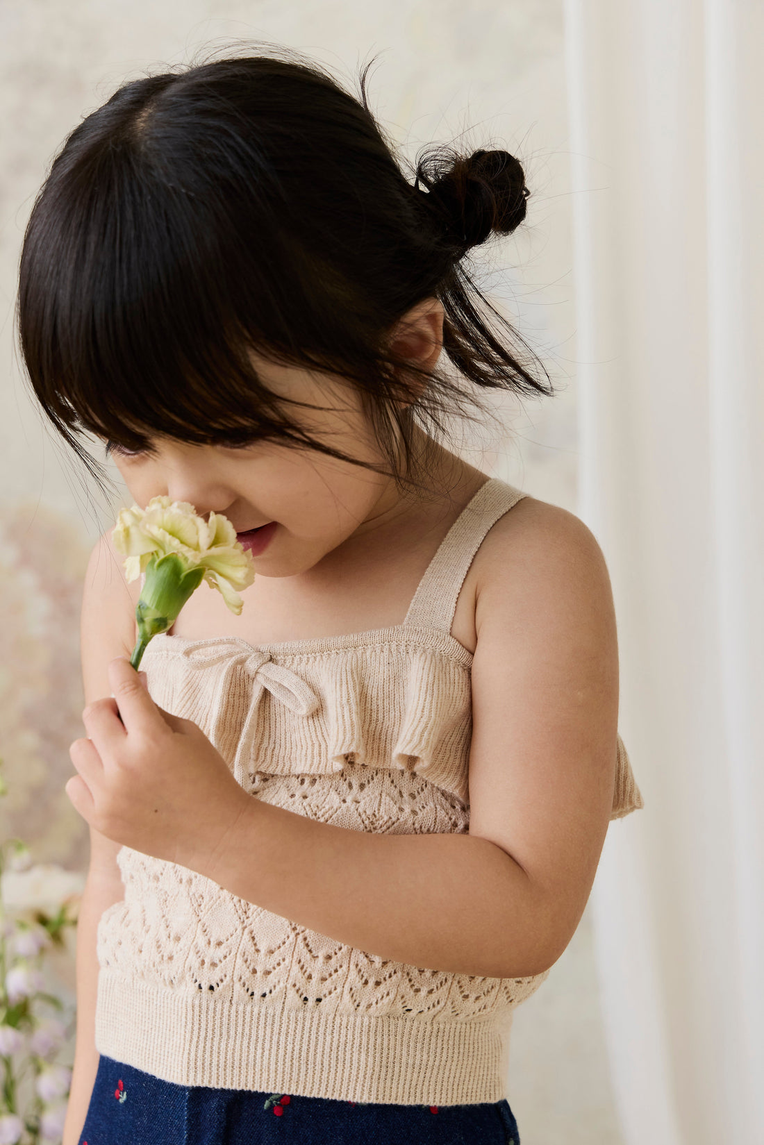 Young girl smelling a flower against a white background