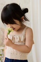 Young girl smelling a flower against a white background