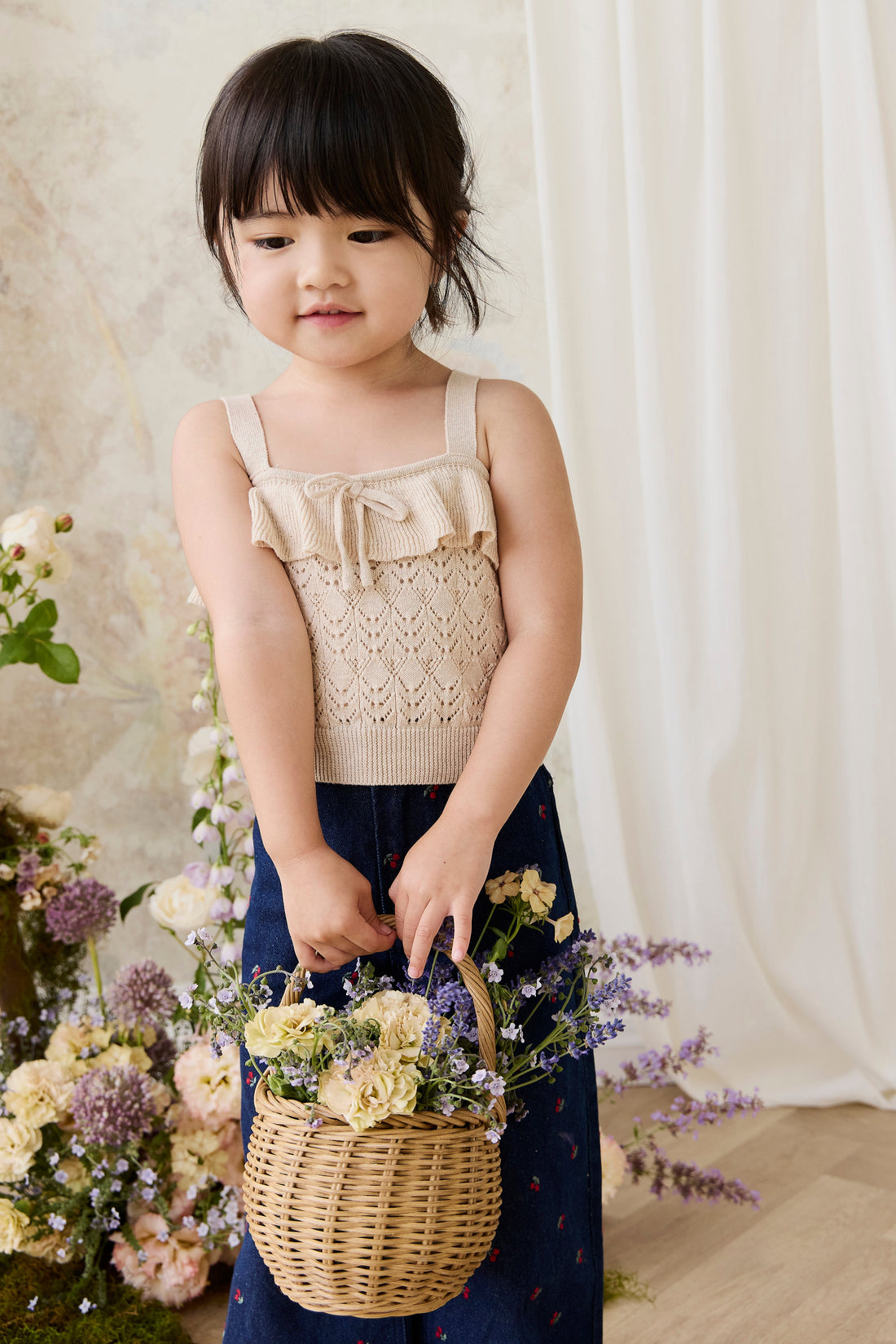 Young girl holding a basket of flowers against a neutral background