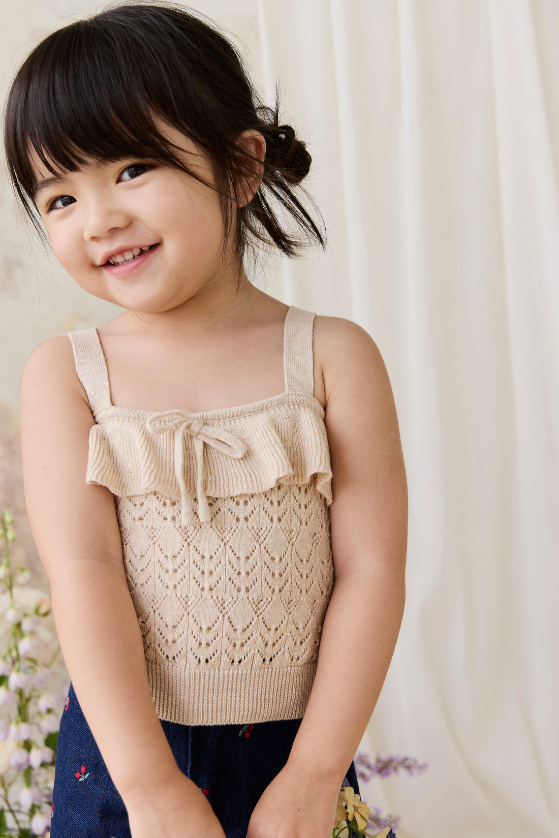 Young girl wearing a beige knitted top with a white background