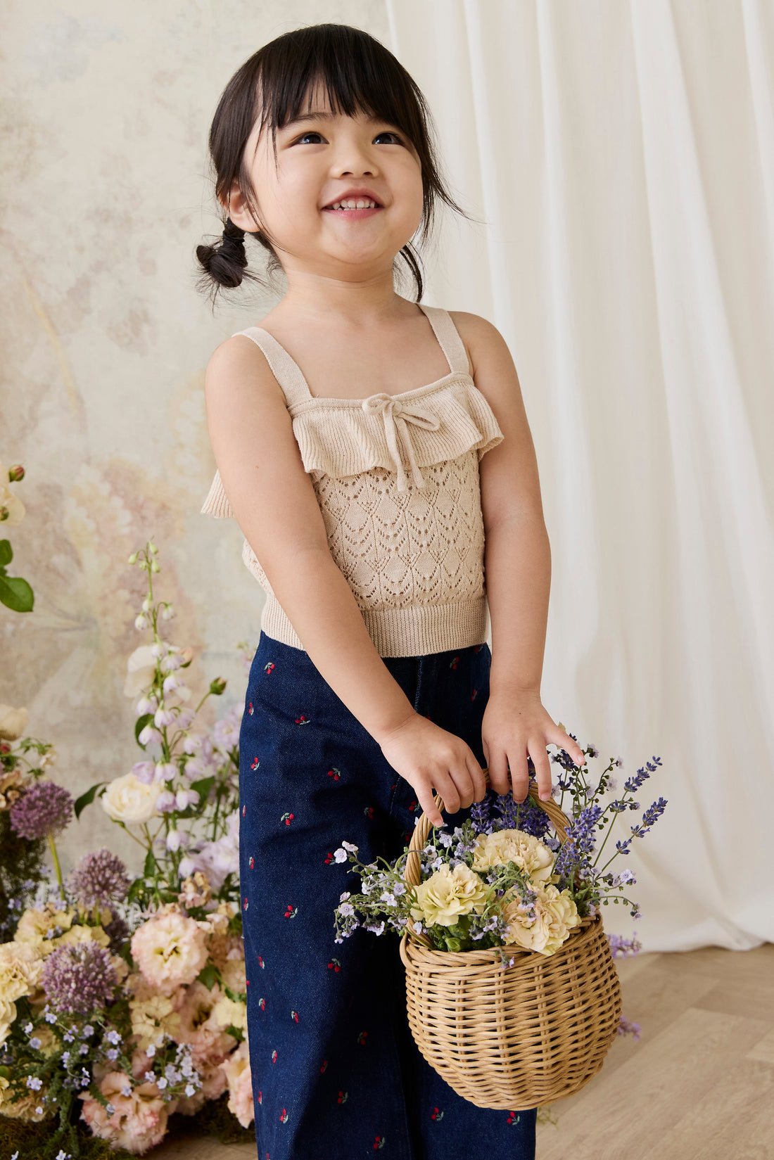 Young girl holding a basket of flowers in a floral setting
