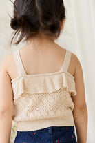 Beige knitted tank top with ruffled details worn by a person against a neutral background