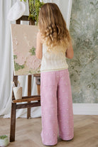 Child painting on an easel with a floral backdrop