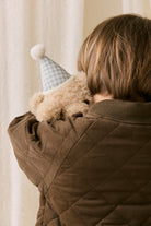 Person holding a teddy bear with a small hat indoors