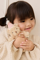 Child wearing a textured cream sweater and holding the Snuggle Bunnies Arthur Keyring by Jamie Kay close to her chest.