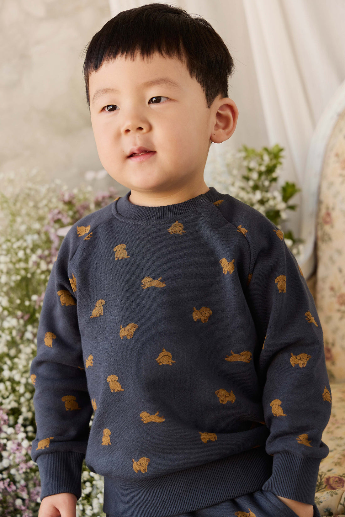 Child wearing a navy sweater with gold animal prints against a floral background