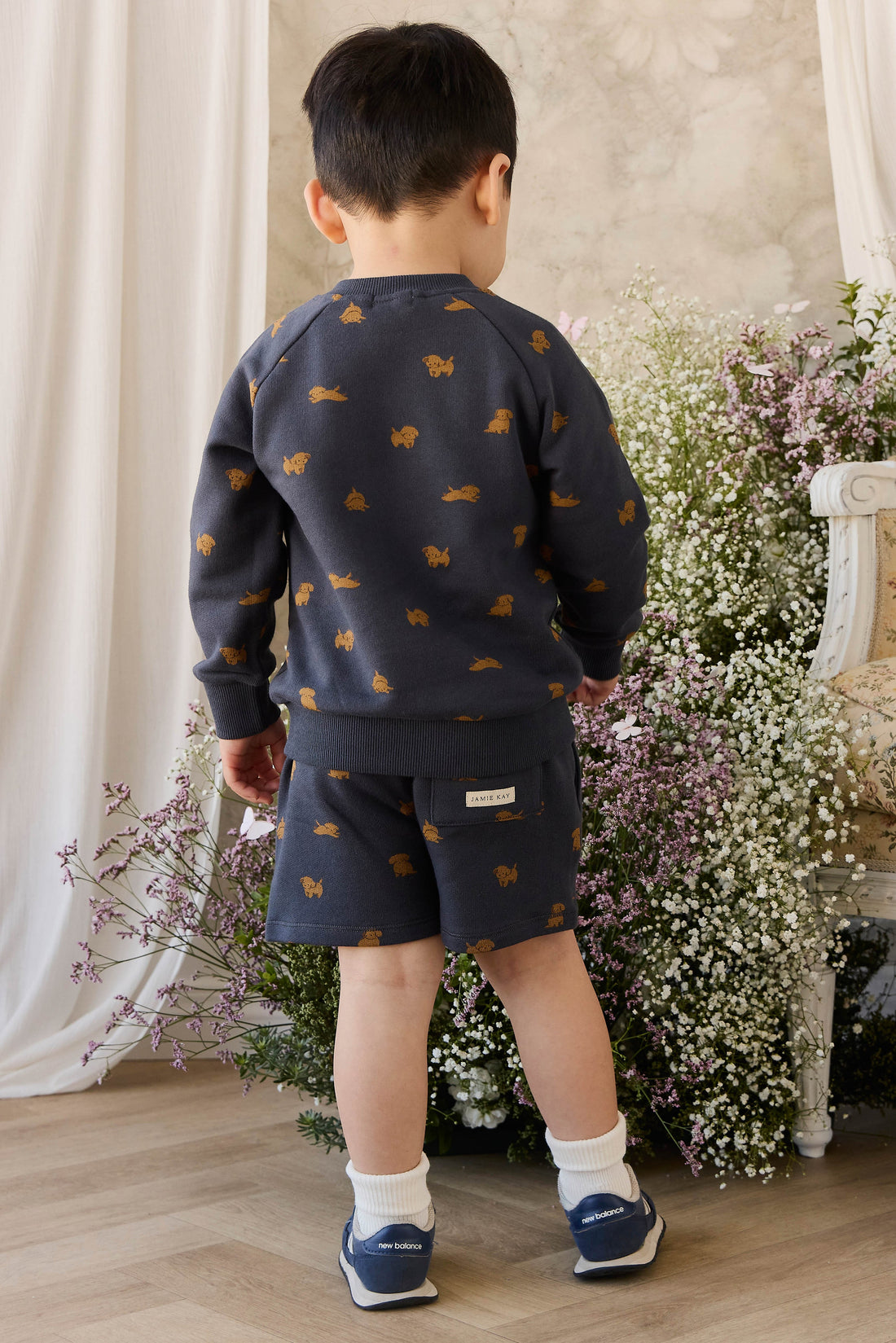 Child wearing a navy blue outfit with fox patterns in a decorated room with flowers.