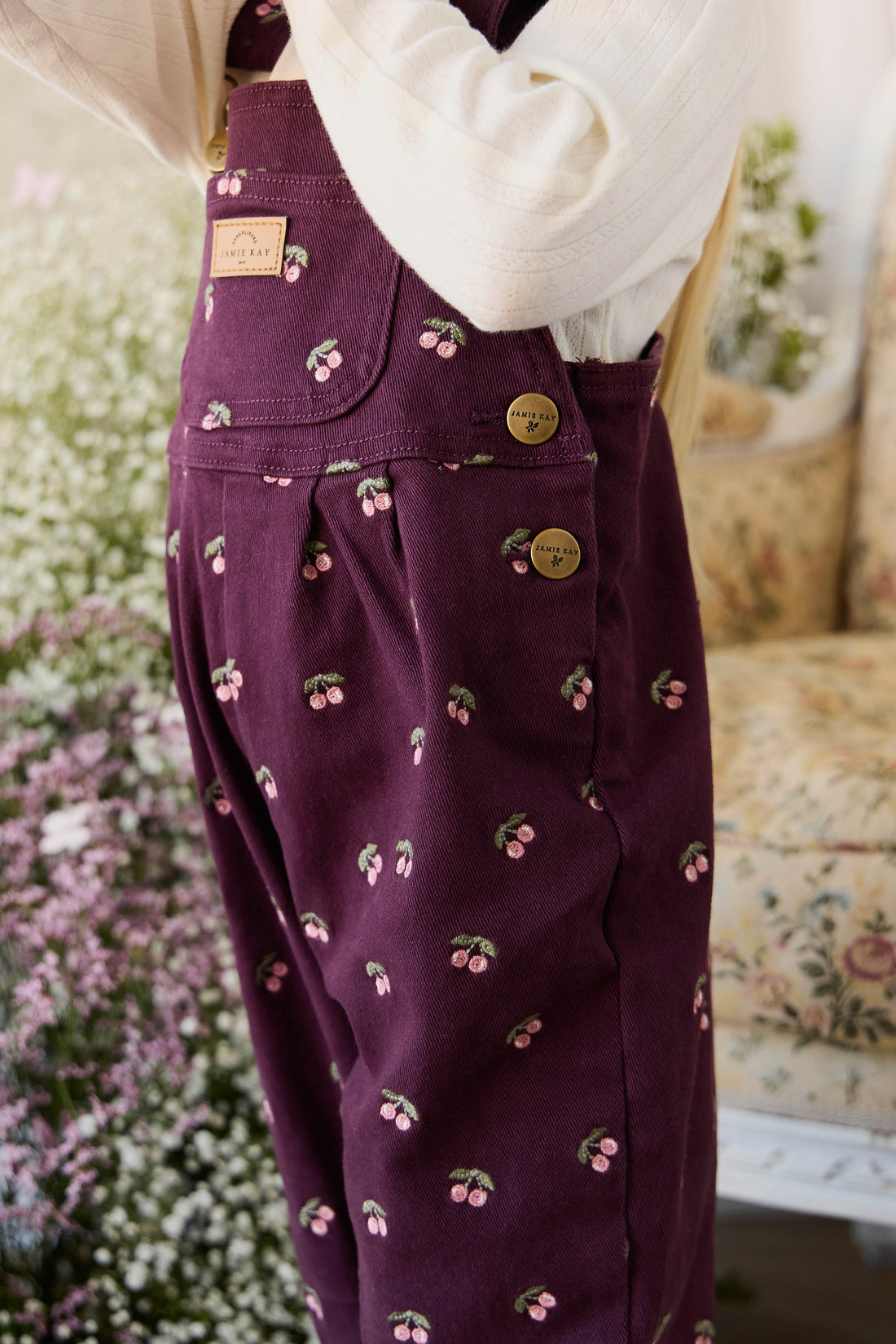 Purple overalls with cherry pattern worn by a person, blurred background