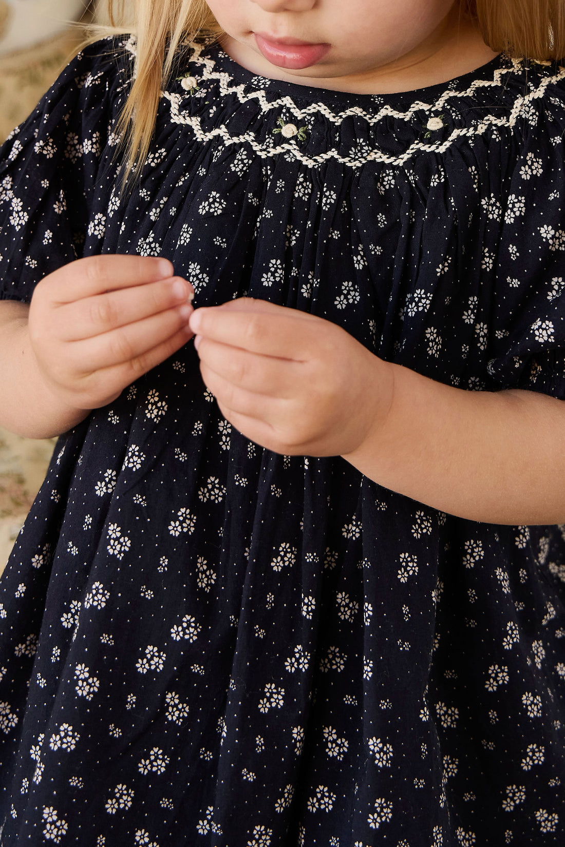 Child wearing a navy blue dress with white floral pattern
