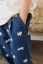 Blue denim pants with white dog prints worn by a person, blurred background