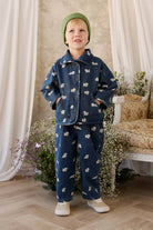 Child wearing a denim outfit with white patterns in a decorated room.