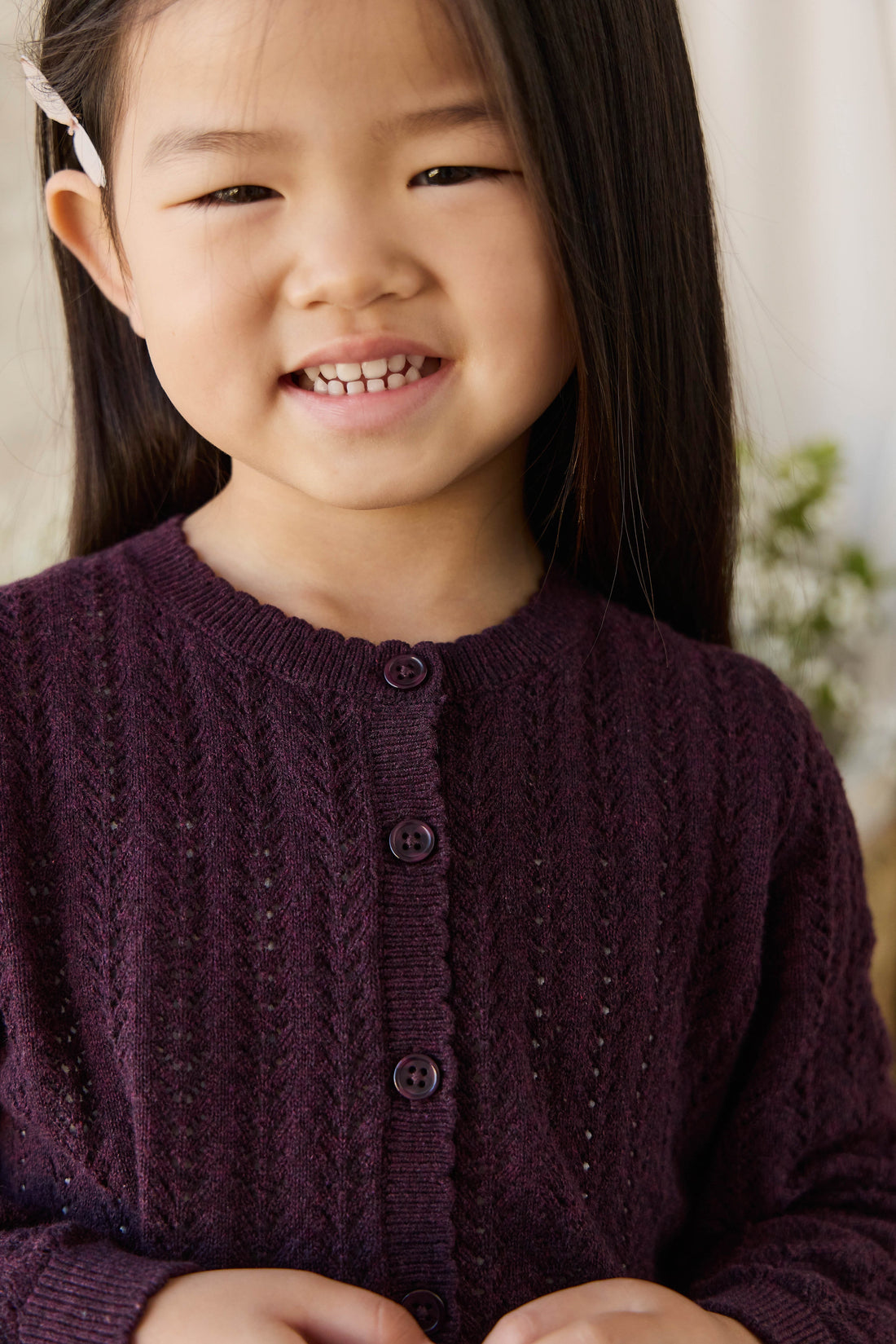 Young girl wearing a purple cardigan with a blurred background
