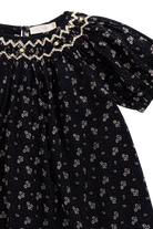 Black dress with floral pattern and ruffled neckline on a white background