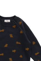 Close-up of a dark navy long-sleeve knit top with small mustard-gold dog motifs repeated across the fabric, shown on a plain white background.