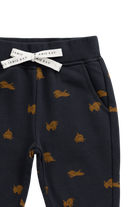 Close-up of a pair of dark navy pants with a repeating tan dog print, featuring a white drawstring bow with the brand name 'Jamie's Kay' printed on it.