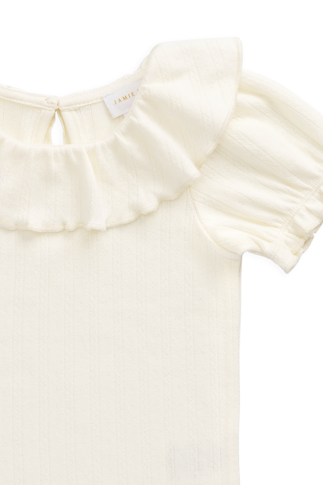 Close-up of a cream-colored baby top with a ruffled collar and short puff sleeves, showing a small interior neck label.