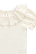 Close-up of a cream-colored baby top with a ruffled collar and short puff sleeves, showing a small interior neck label.