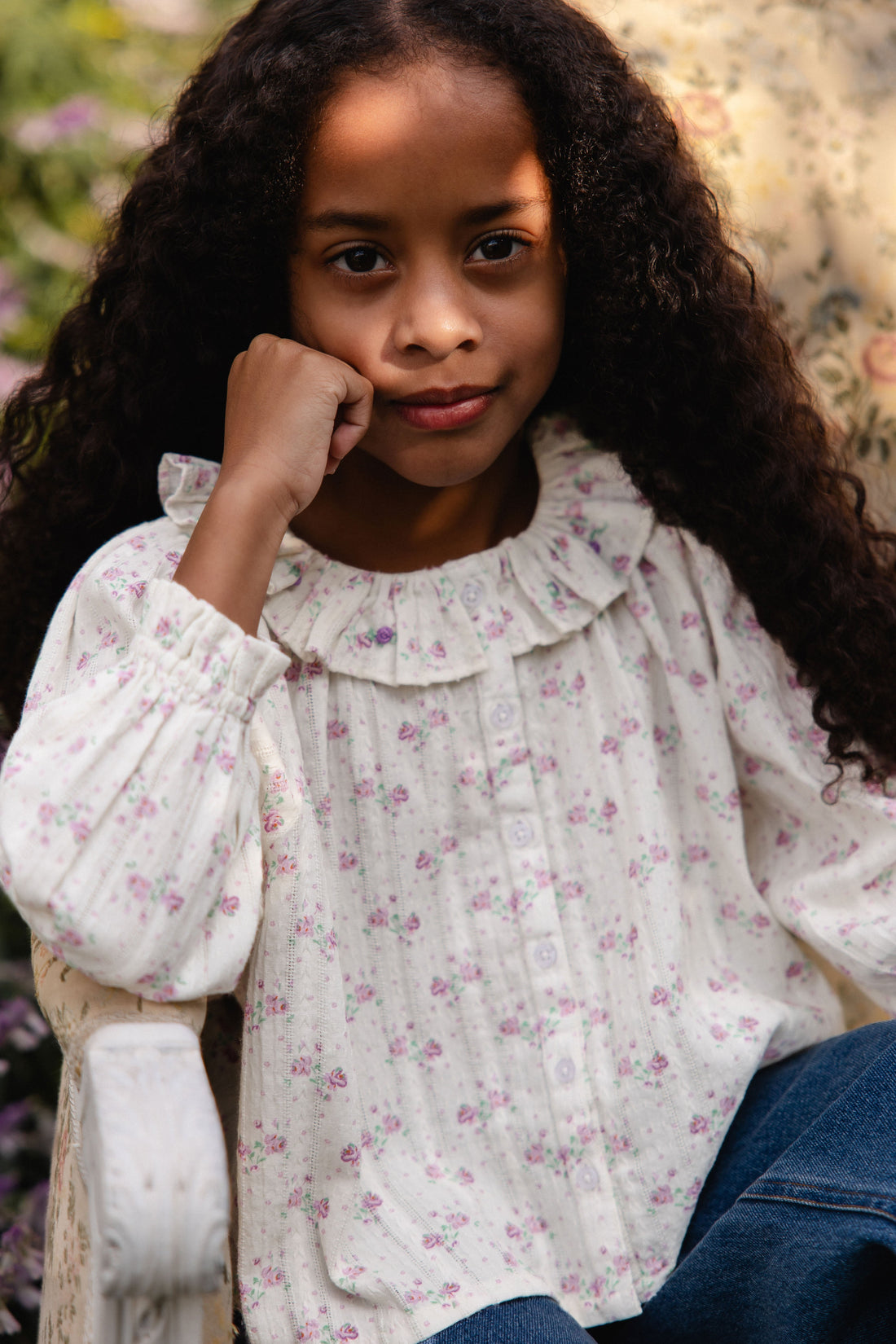Young girl wearing a floral blouse with a blurred floral background