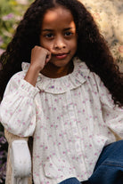 Young girl wearing a floral blouse with a blurred floral background