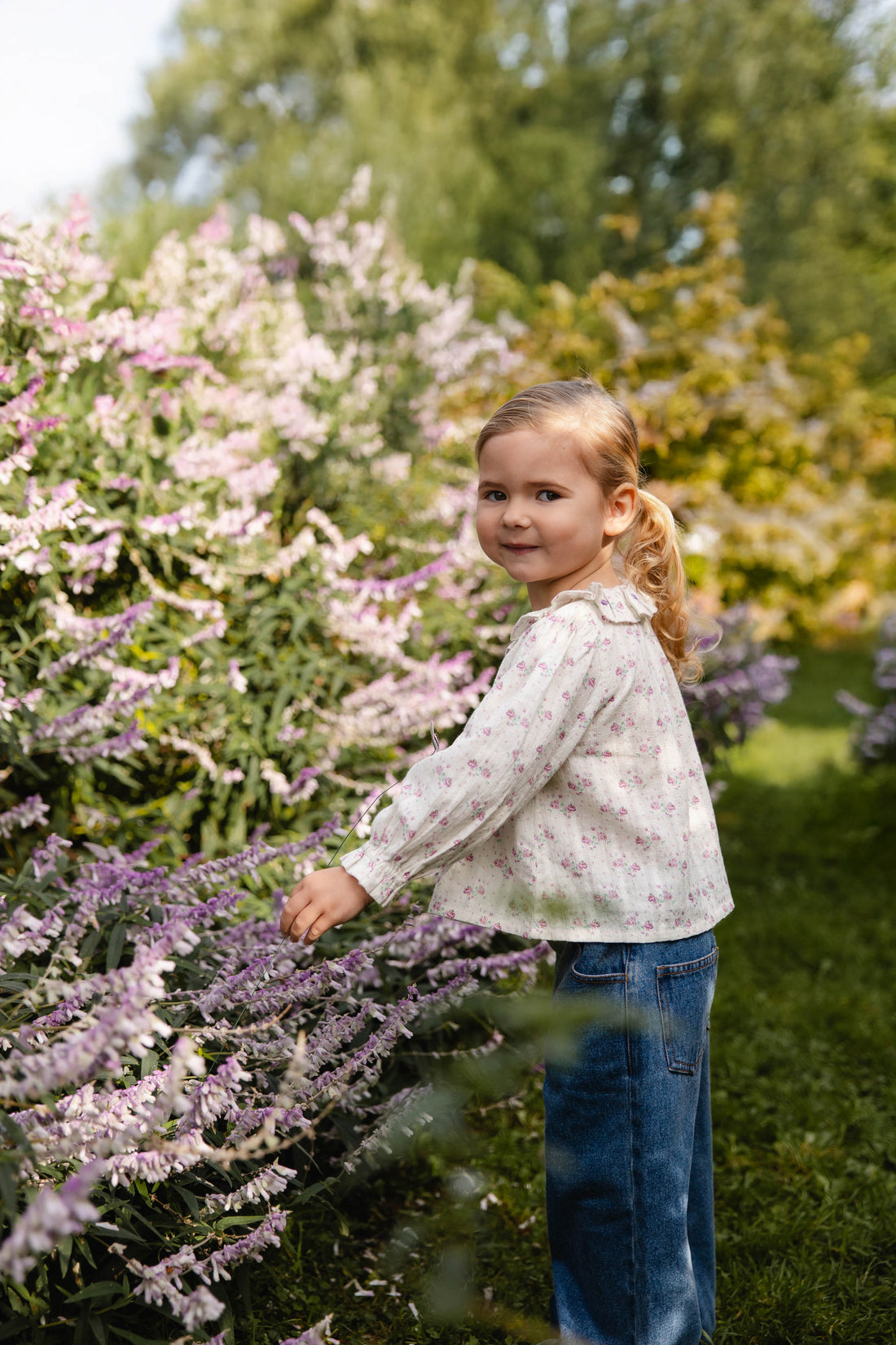 Young girl standing among purple flowers in a garden