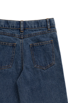 Close-up of the back waistband and pockets of dark blue denim jeans on a white background.