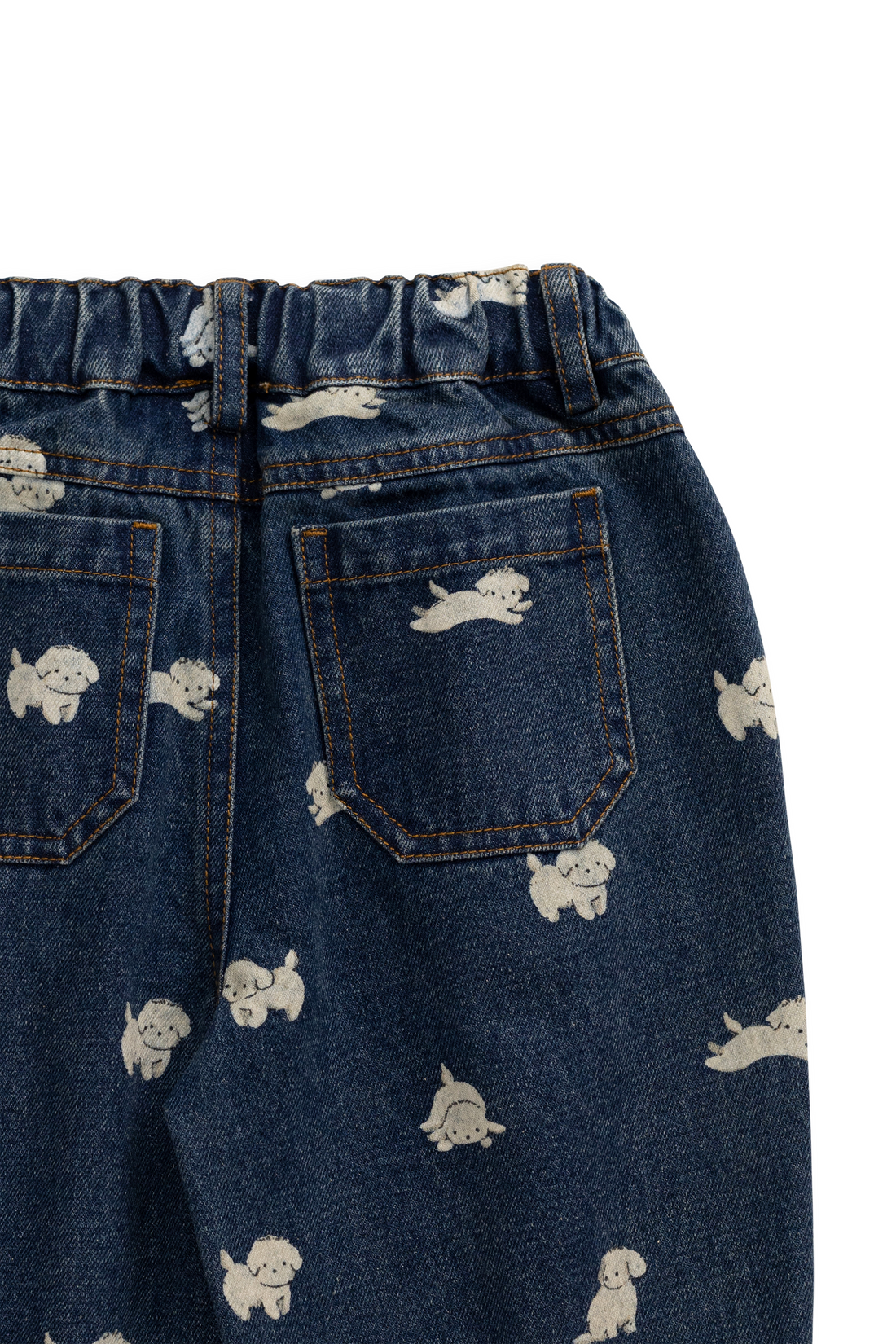 Close-up of the back of dark blue denim jeans with an elastic waistband, two back pockets, and a scattered white cartoon dog print on a white background.