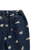 Close-up of the back of dark blue denim jeans with an elastic waistband, two back pockets, and a scattered white cartoon dog print on a white background.
