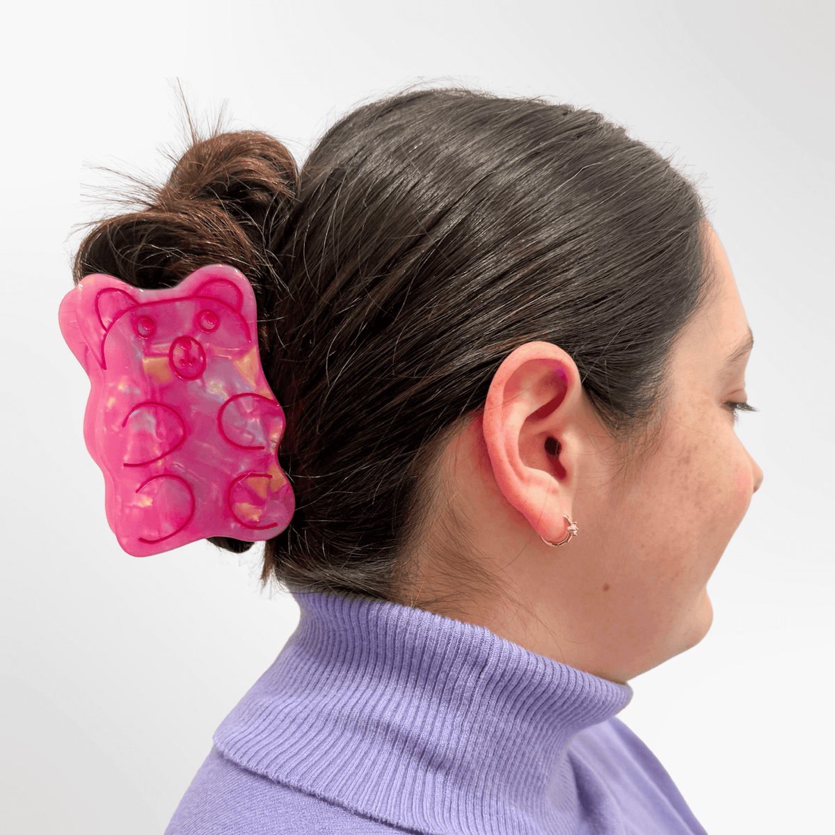 Person wearing a pink butterfly hair clip on a white background