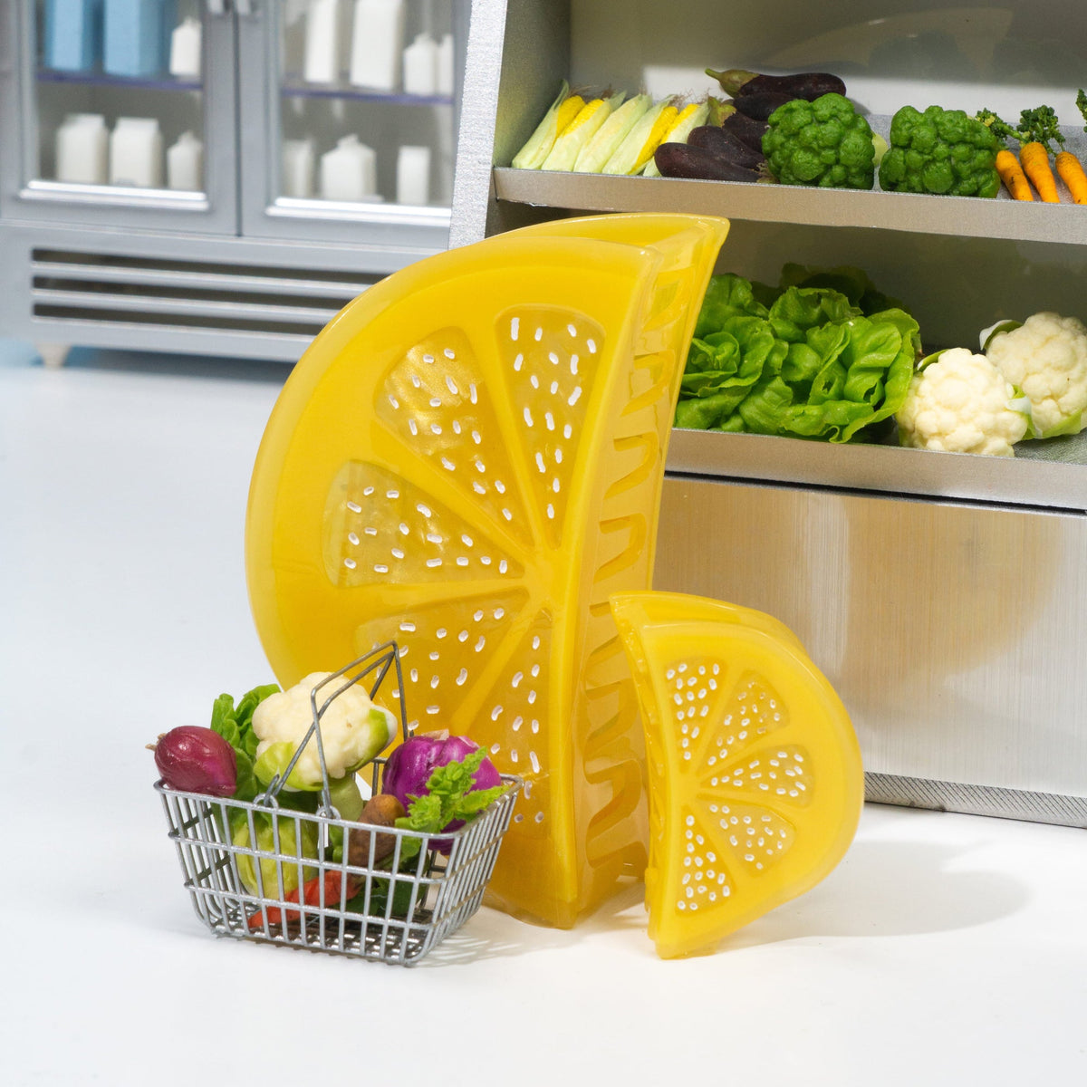 Yellow lemon-shaped kitchen tool on a counter with a refrigerator and shelves of vegetables in the background.