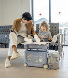 Person and child using a travel seat in an airport lounge.