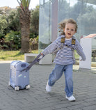 Child pulling a small suitcase on wheels outdoors