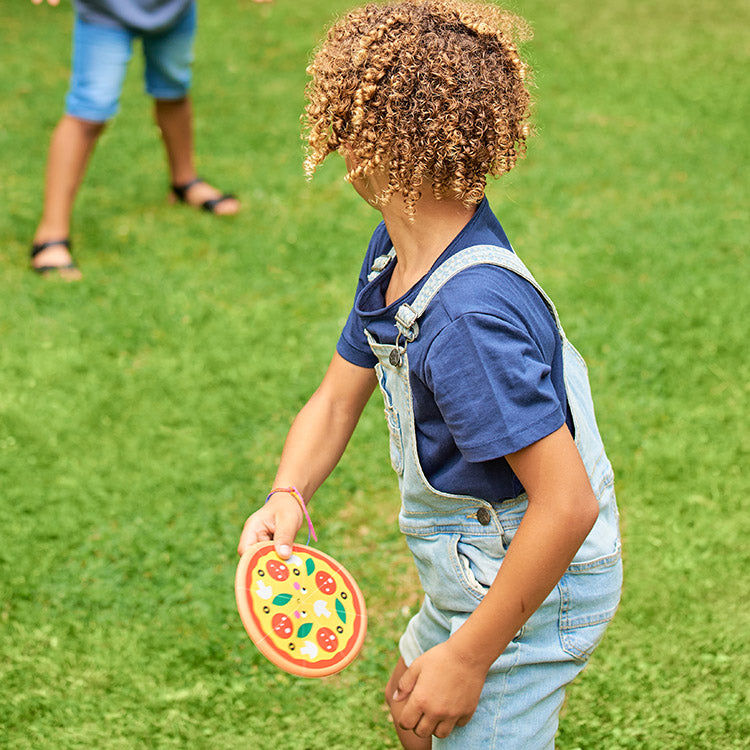 Child holding a colorful frisbee on a grassy field