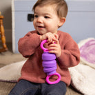 Child holding a purple and pink toy in a home setting