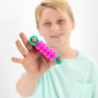 Person holding a pink and green resistance band with a blurred background