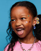Child wearing colorful earrings and jewelry against a blue background