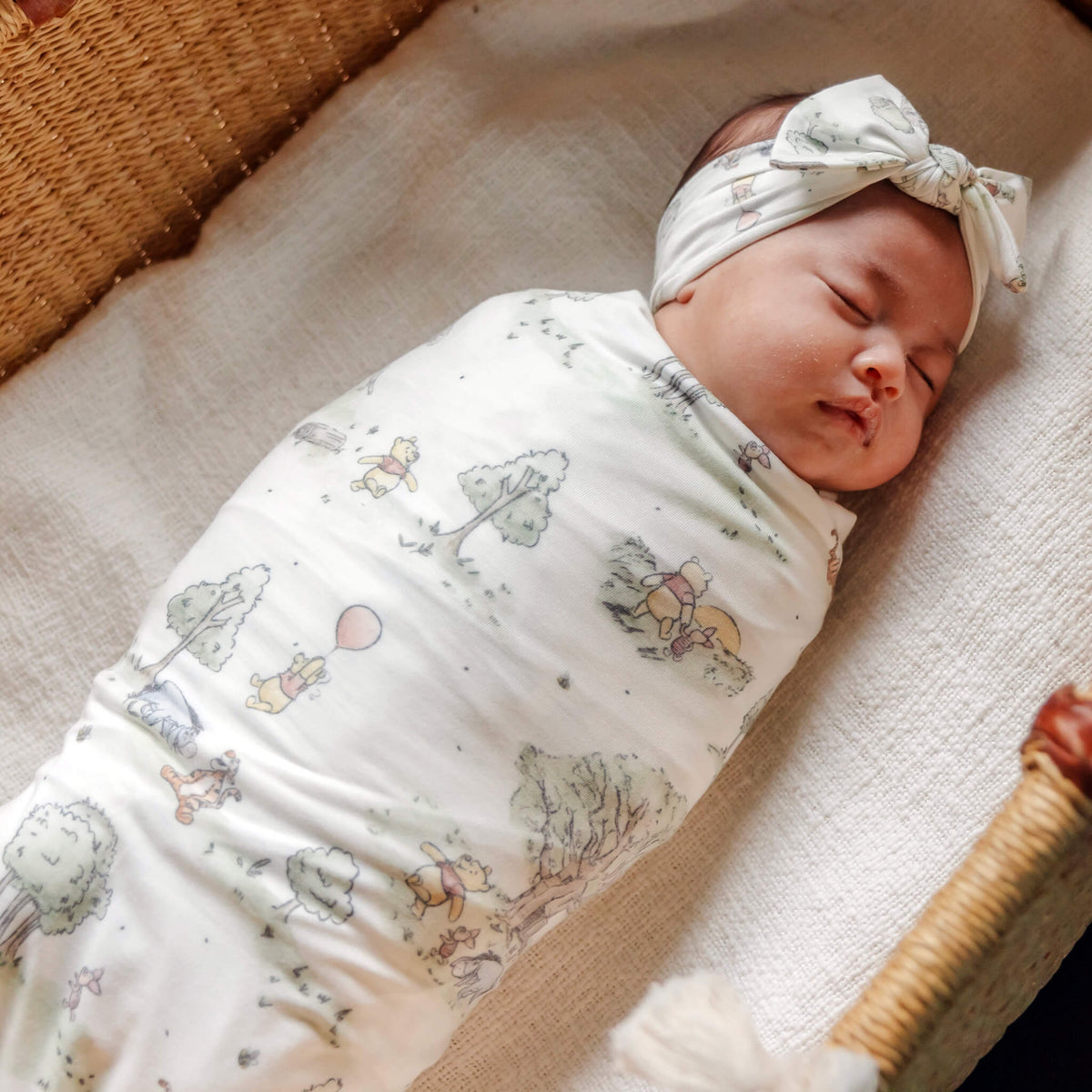 Baby wrapped in a blanket with a hat on a wooden surface