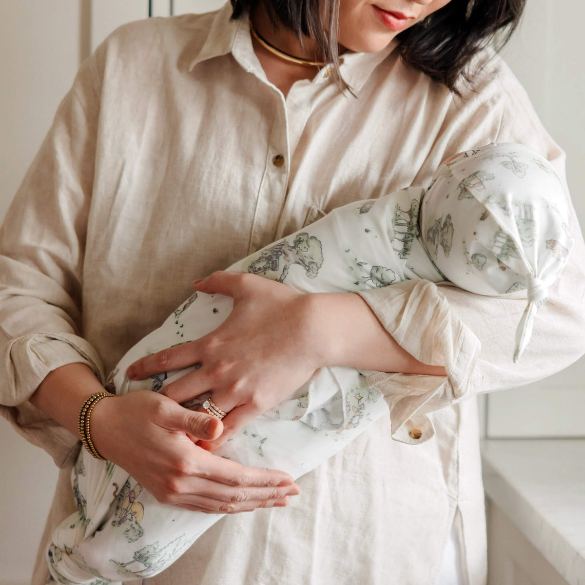 Person wearing a beige shirt holding a white garment with floral patterns.