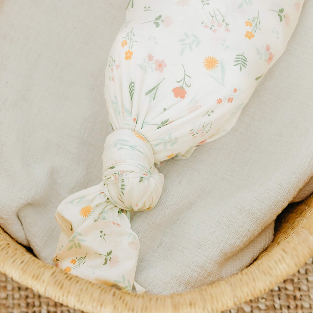 Floral-patterned swaddle blanket tied in a knot on a textured surface