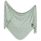 A green knit swaddle blanket with a subtle star pattern.