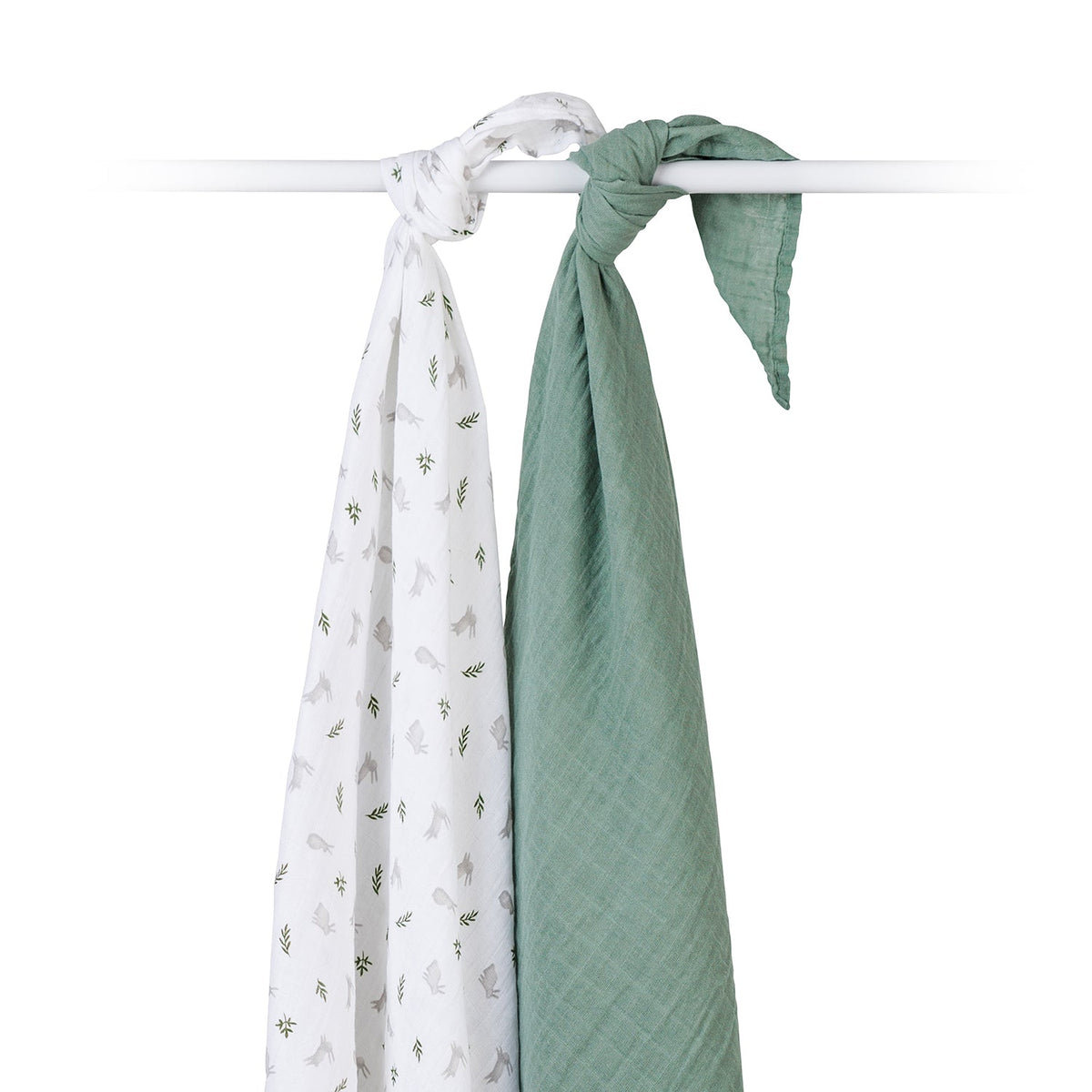 Two muslin baby swaddle blankets hanging from a white rod against a white background. One blanket is white with a small sage green botanical pattern, and the other is a solid sage green color.