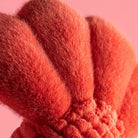 Close-up of a fluffy red object against a pink background
