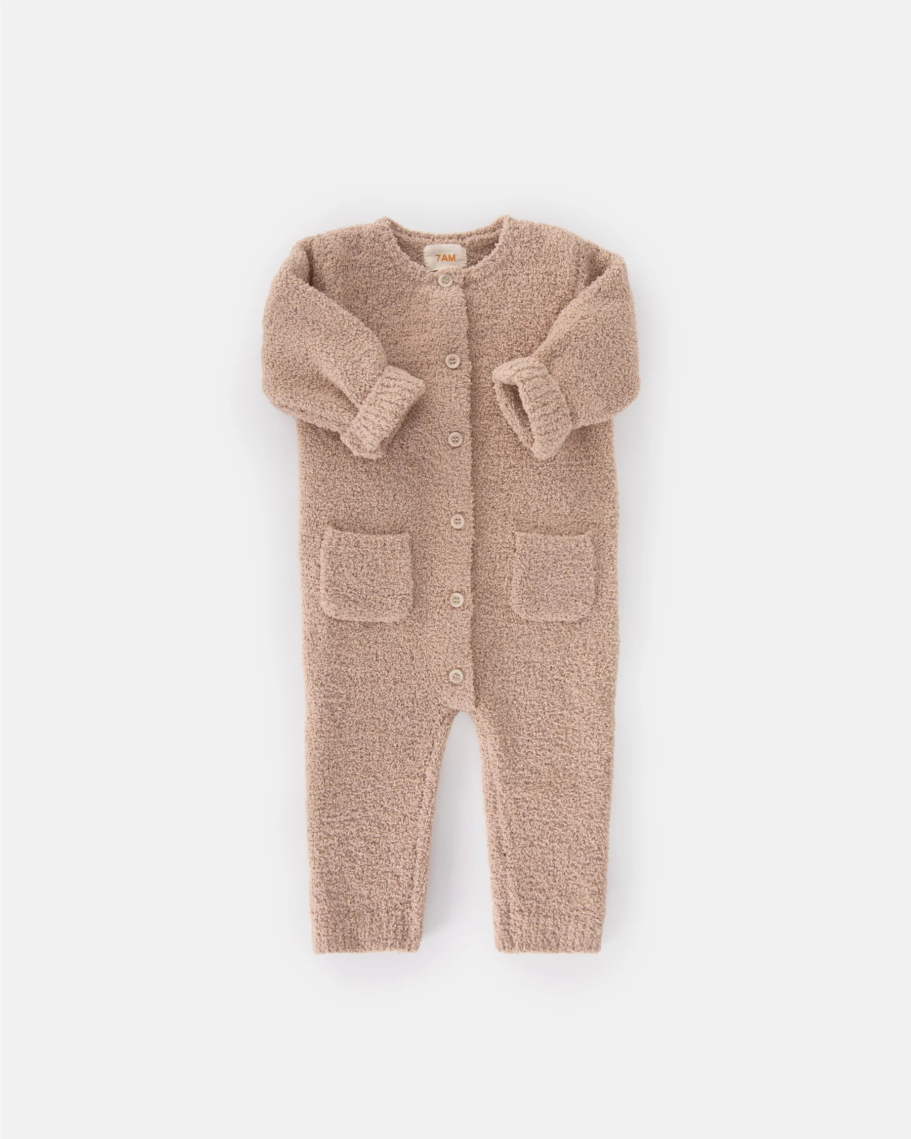 A soft, long-sleeve fuzzy romper in a warm pecan brown color by 7AM Enfant, featuring a round neckline, a full-length center button closure, ribbed cuffs and ankles, and two front pockets, laid flat on a white background.