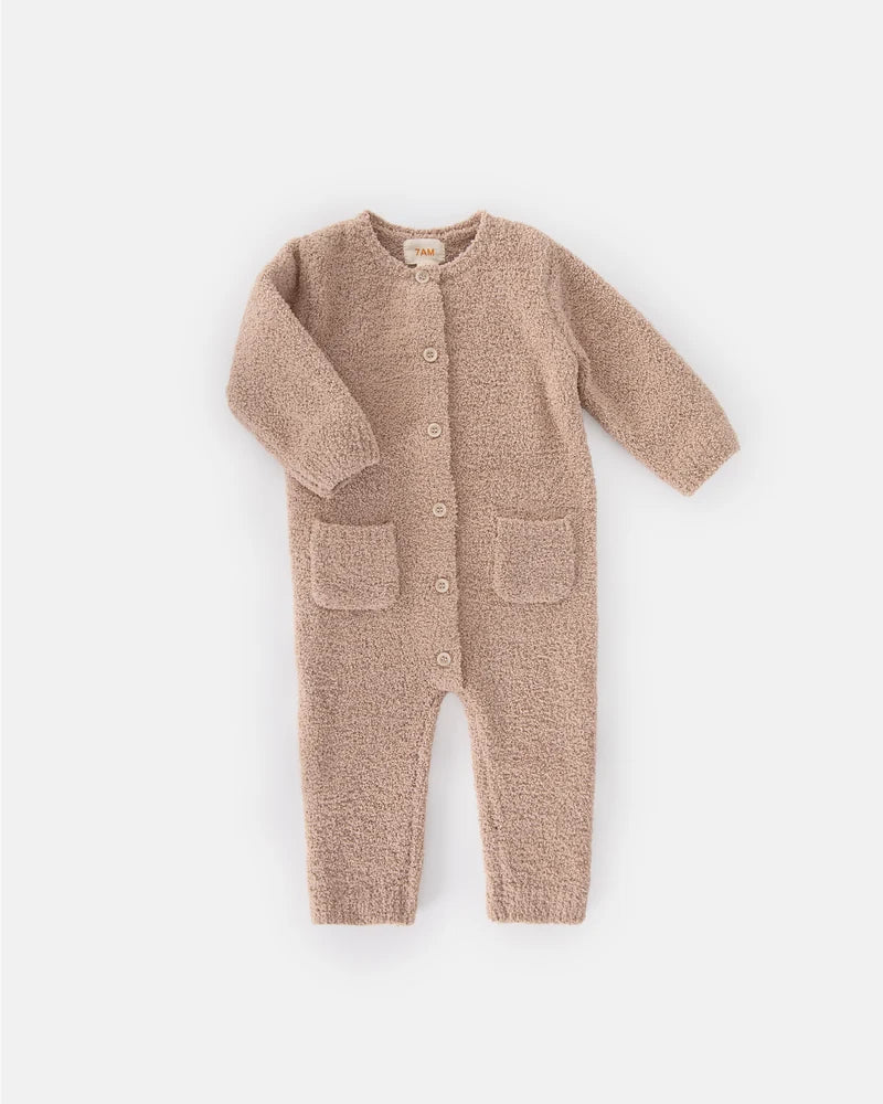 A soft, long-sleeve fuzzy romper in a warm pecan brown color by 7AM Enfant, featuring a round neckline, a full-length center button closure, ribbed cuffs and ankles, and two front pockets, laid flat on a white background.